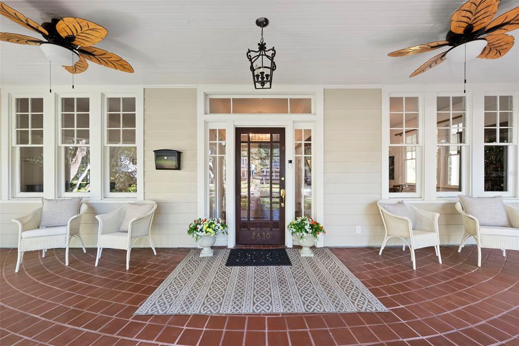 A covered front porch features a tiled floor, four wicker chairs, and two ceiling fans — 2630 W PROSPECT ROAD, TAMPA, FL