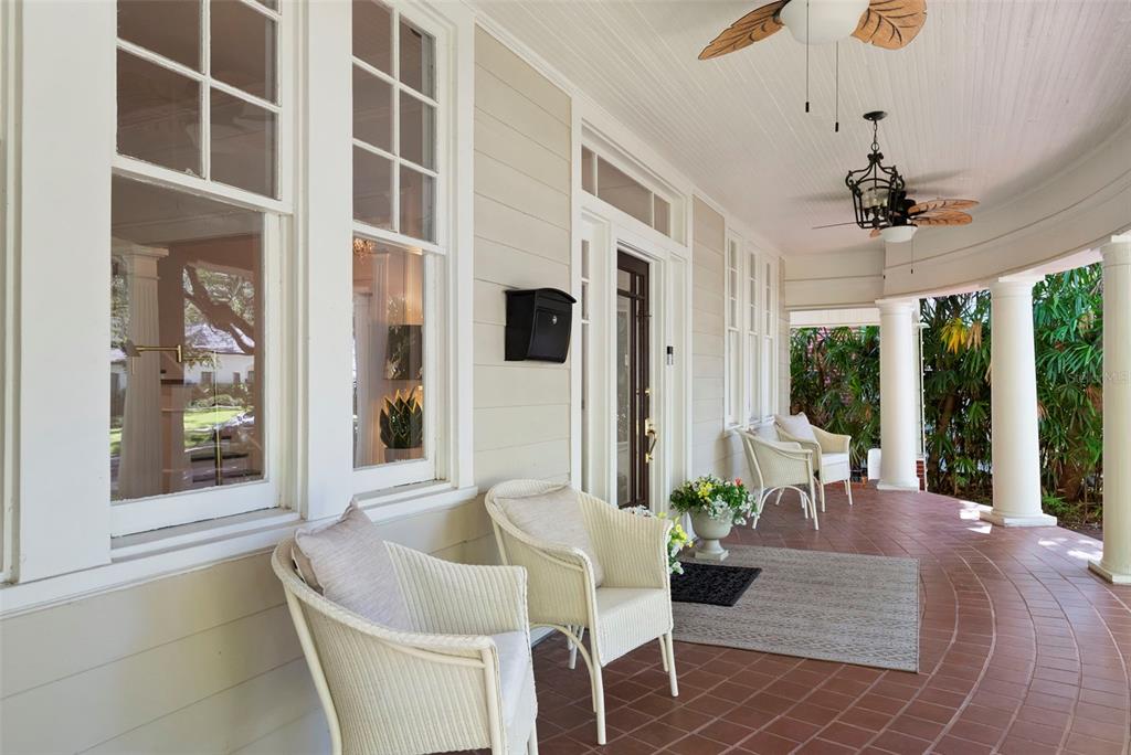 A covered porch features white wicker chairs, a tiled floor, and columns along the exterior — 2630 W PROSPECT ROAD, TAMPA, FL