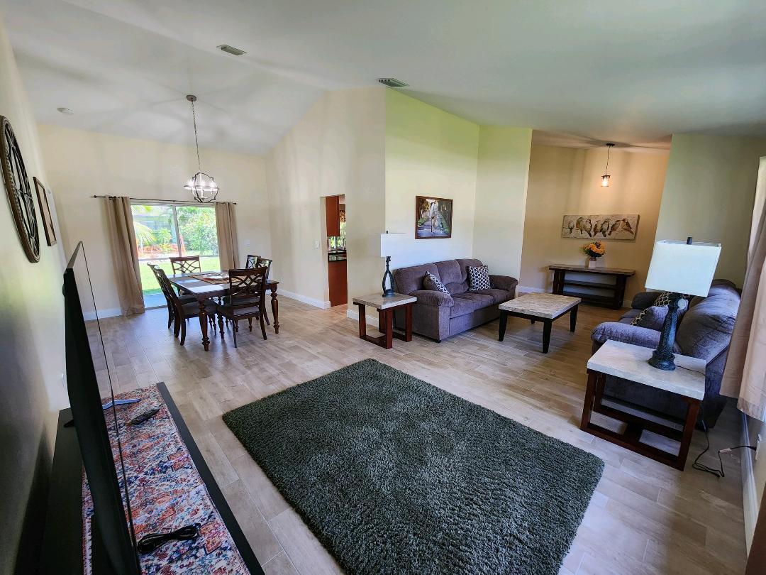 A living and dining area with vaulted ceilings, tile flooring, and a large area rug — 1750 Primrose Lane, Wellington FL 33414, WELLINGTON, FL