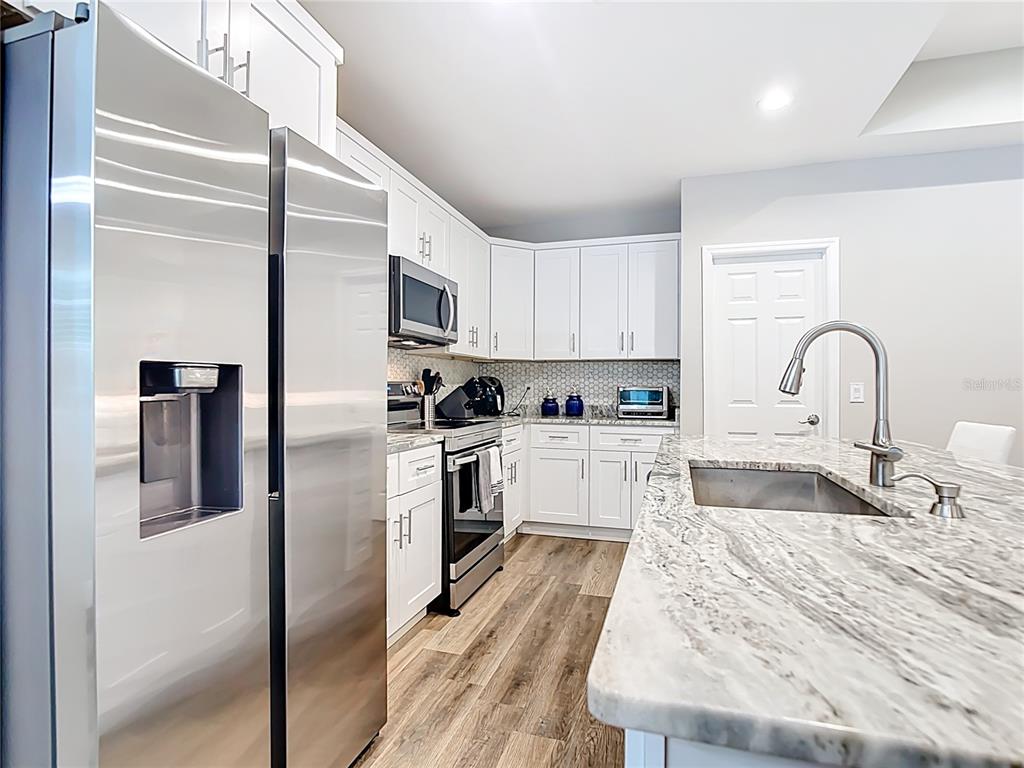 A kitchen features white cabinets, stainless steel appliances, and a marble-patterned island countertop — 5153 PINSON DRIVE, NORTH PORT, FL
