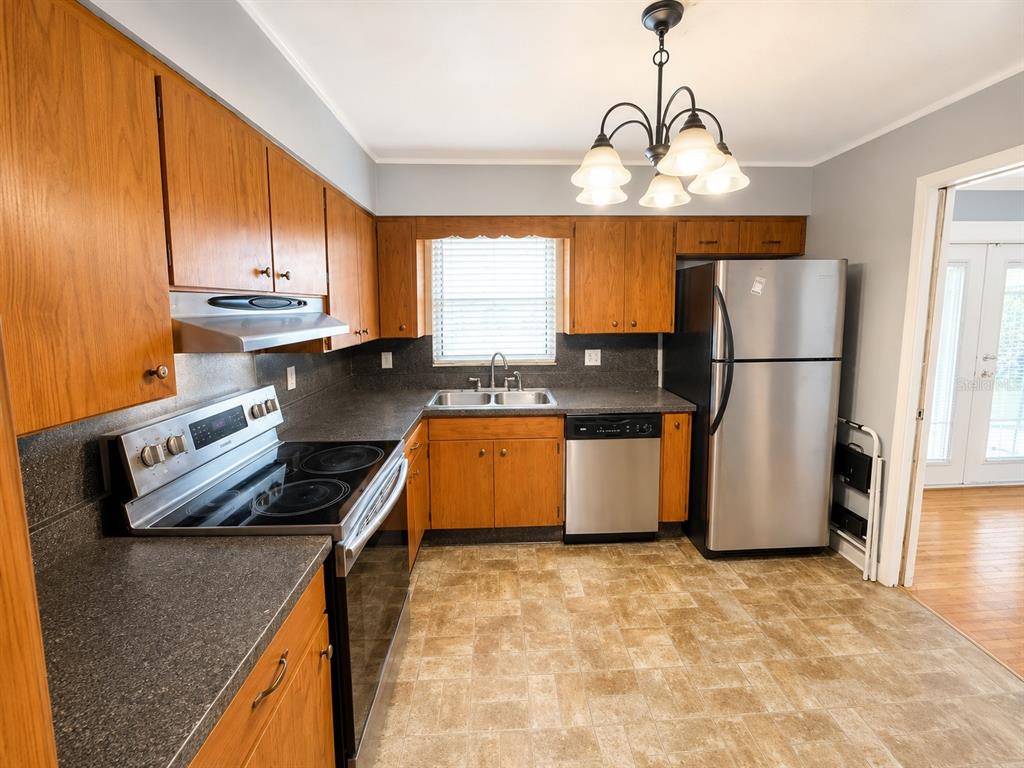 A kitchen with wood cabinets, dark countertops, stainless steel appliances, and a tile floor — 409 MONTGOMERY AVENUE, LAKELAND, FL