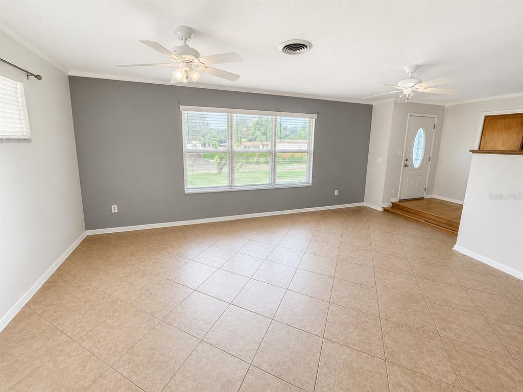 A living room features light tile flooring, a gray accent wall, and two ceiling fans — 409 MONTGOMERY AVENUE, LAKELAND, FL