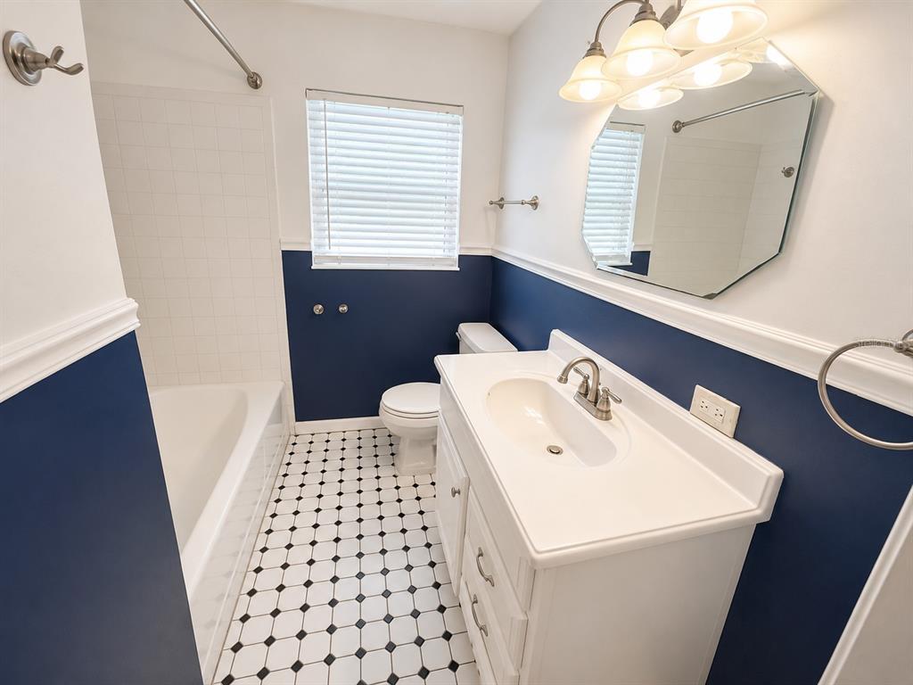 A bathroom features a white vanity, a tub-shower combo, and navy blue walls with tile — 409 MONTGOMERY AVENUE, LAKELAND, FL