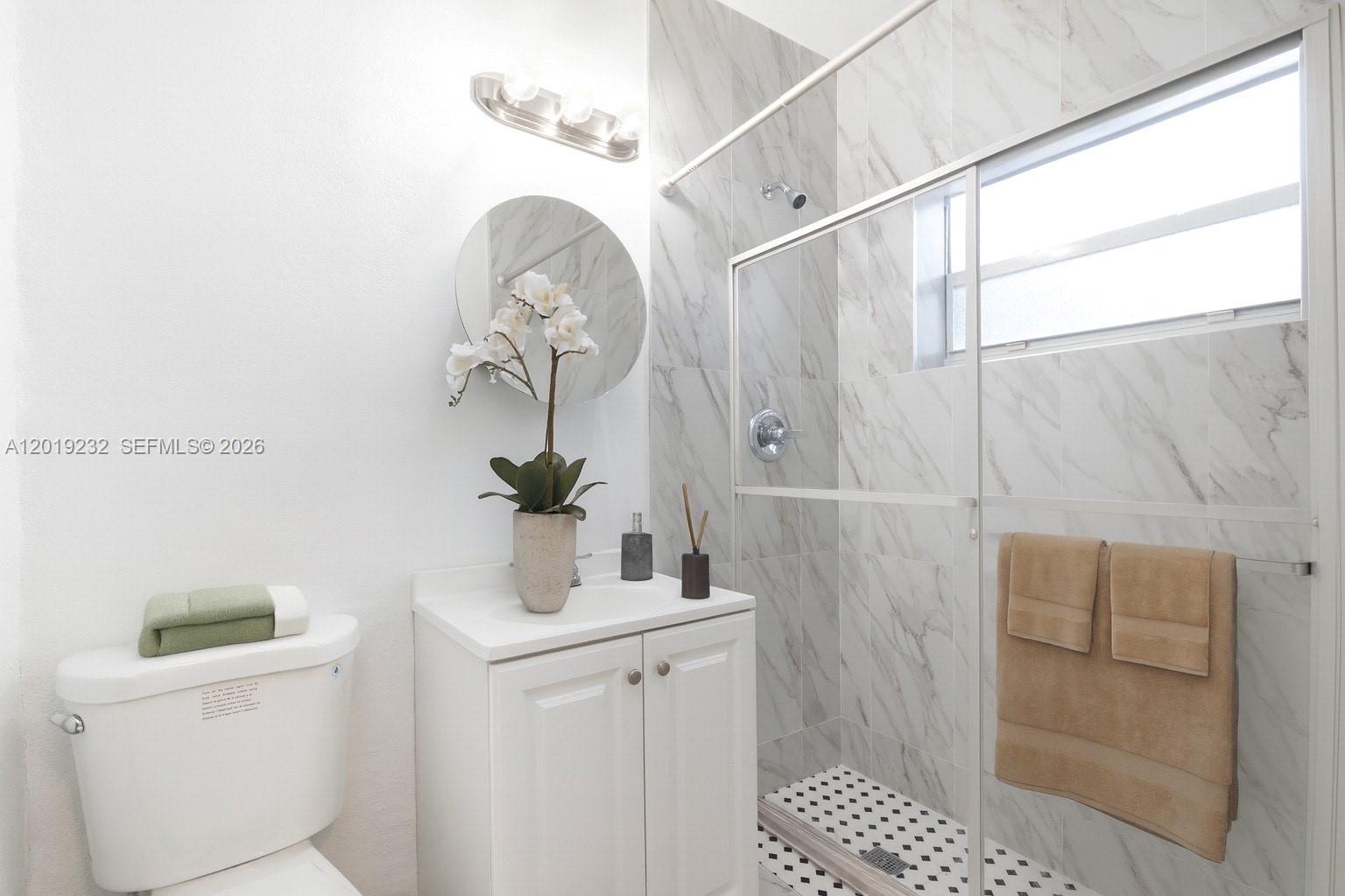A bathroom features a white vanity, a toilet, and a walk-in shower with marble-look tiles — 1450 SW 6th St # 9, Miami FL 33135, MIAMI, FL