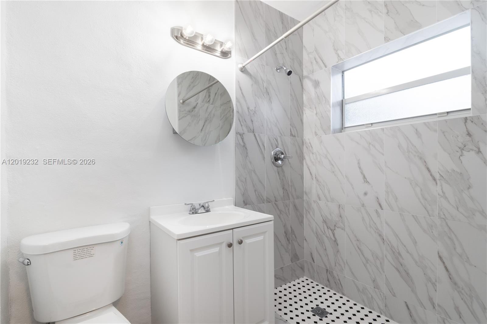 A bathroom features a white vanity, a toilet, and a shower with marble-patterned wall tiles — 1450 SW 6th St # 9, Miami FL 33135, MIAMI, FL