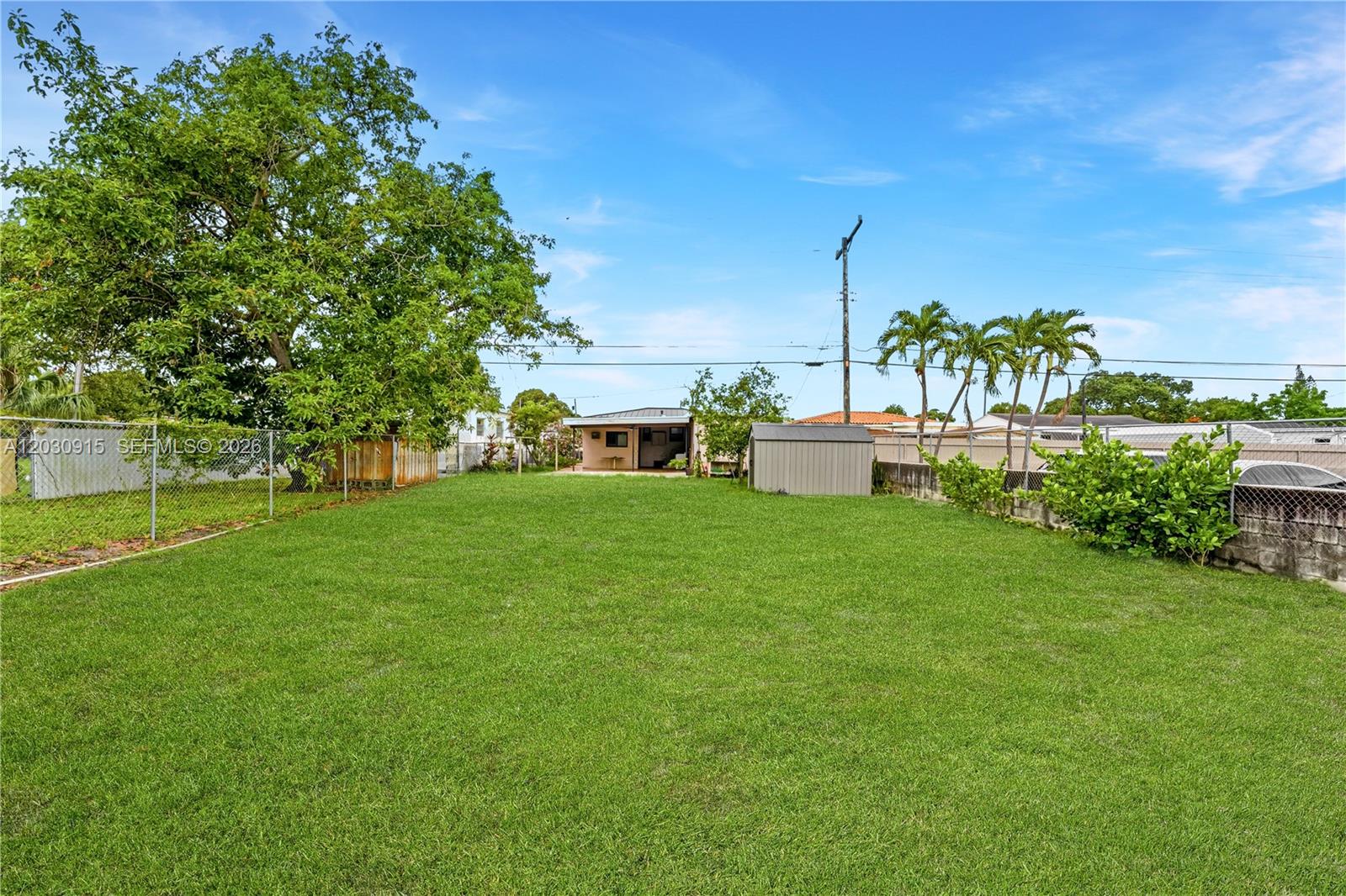 A large, grassy backyard features a small storage shed, a house, and palm trees — 121 SW 71st Ave, Miami FL 33144, MIAMI, FL