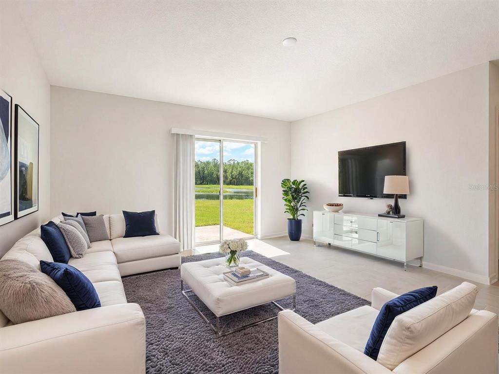 A living room features a white sectional sofa, a matching ottoman, and a view of a pond — 1187 CABOT CLIFFS DRIVE, DAYTONA BEACH, FL