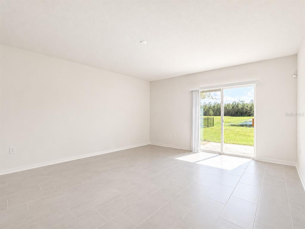 An empty room with light-colored tile flooring and a sliding glass door leading outside — 1187 CABOT CLIFFS DRIVE, DAYTONA BEACH, FL