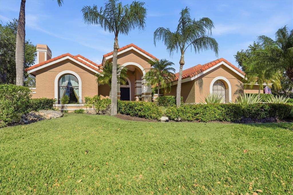 A tan single-story house with a tile roof, arched windows, and palm trees in front — 4221 ESCONDITO CIRCLE, SARASOTA, FL