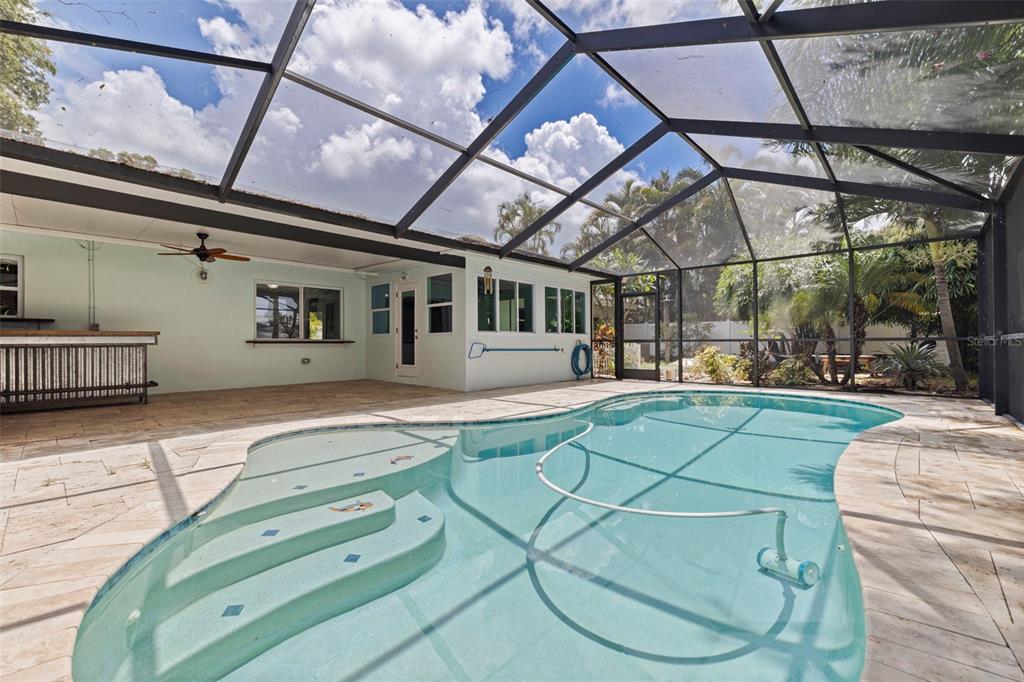 A screened-in patio features a swimming pool with steps and a built-in outdoor bar — 13555 CROFT DRIVE N, LARGO, FL