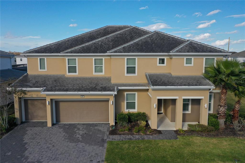 An exterior view of a two-story tan house with a gray tiled roof and garage — 3801 SONOMA BOULEVARD, KISSIMMEE, FL