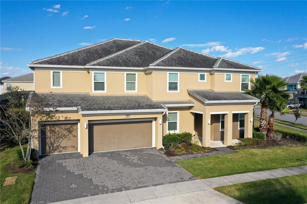A two-story house with a tan stucco exterior, a gray tile roof, and a garage — 3801 SONOMA BOULEVARD, KISSIMMEE, FL