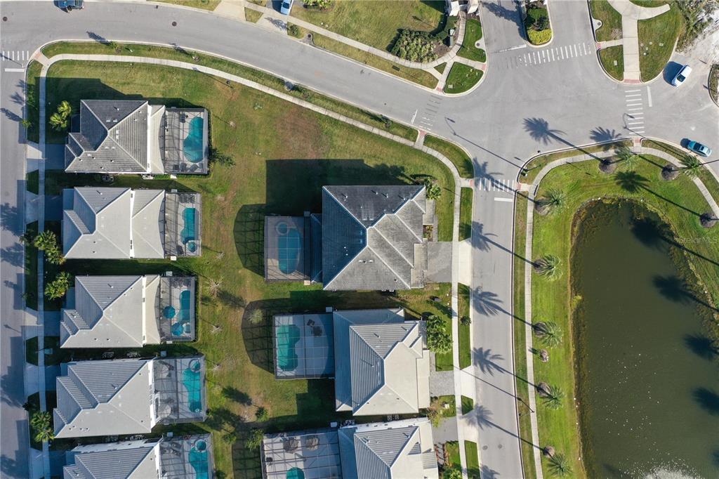 An aerial view shows a residential neighborhood with houses, swimming pools, and a nearby pond — 3801 SONOMA BOULEVARD, KISSIMMEE, FL