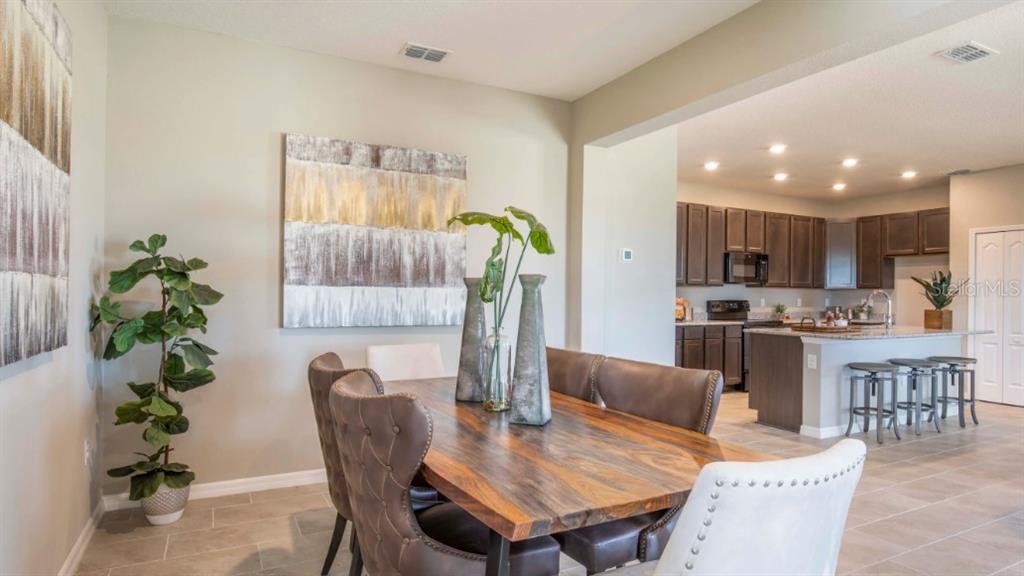 A dining room with a wooden table and chairs sits adjacent to an open kitchen — 74 ENCLAVE AVENUE, PALM COAST, FL