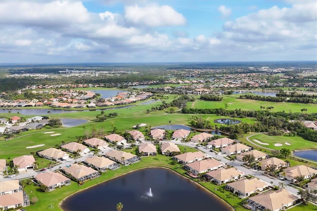An aerial view of a residential neighborhood surrounding a lake with a fountain and golf course — 4301 WHISPERING OAKS DRIVE, NORTH PORT, FL