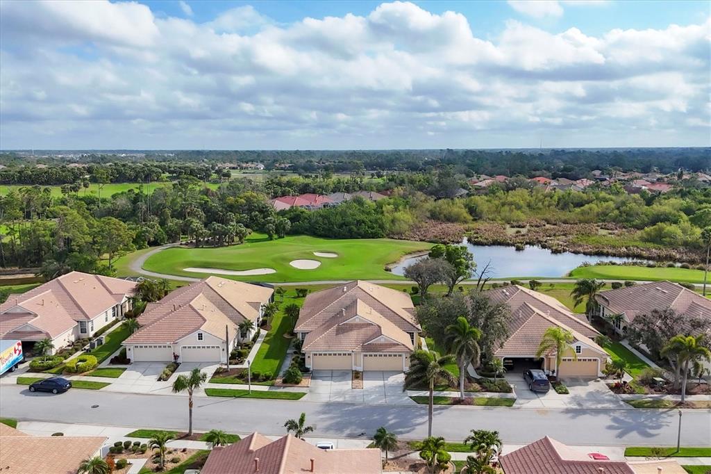 An aerial view shows a row of suburban houses overlooking a golf course and pond — 4301 WHISPERING OAKS DRIVE, NORTH PORT, FL