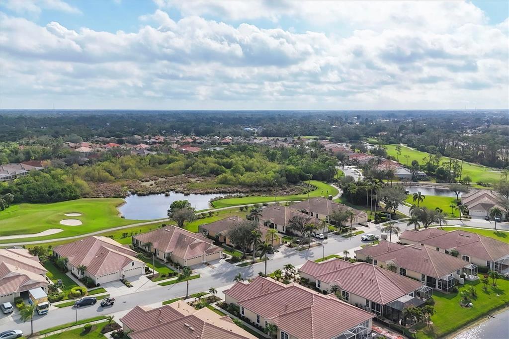 An aerial view shows a suburban neighborhood with houses, a pond, and a golf course — 4301 WHISPERING OAKS DRIVE, NORTH PORT, FL