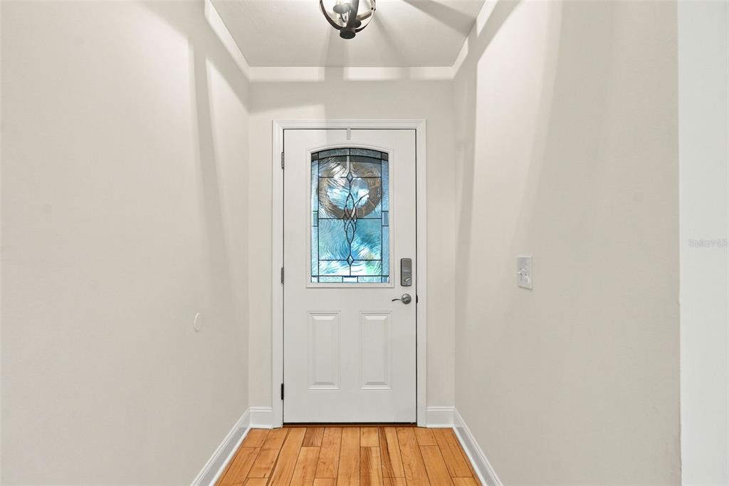An entryway features a white front door with a decorative glass insert and wood flooring — 934 BERKLEY COURT N, PALM HARBOR, FL