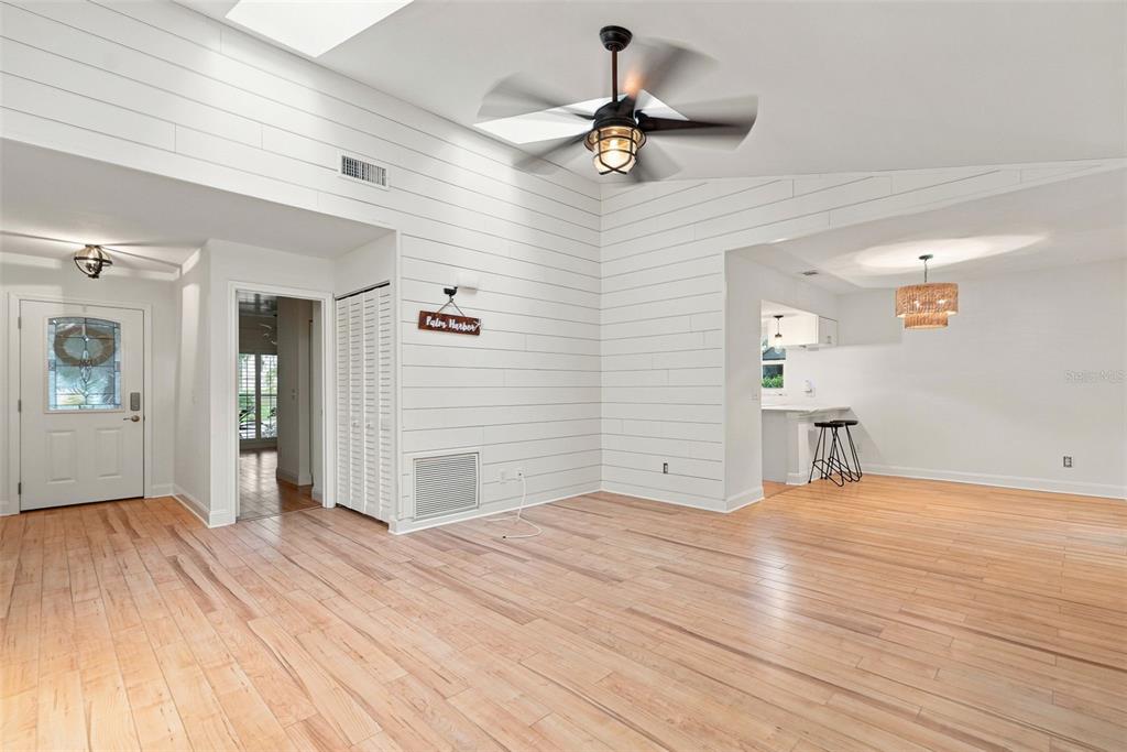 A bright living room features white shiplap walls, vaulted ceilings, and light wood flooring — 934 BERKLEY COURT N, PALM HARBOR, FL