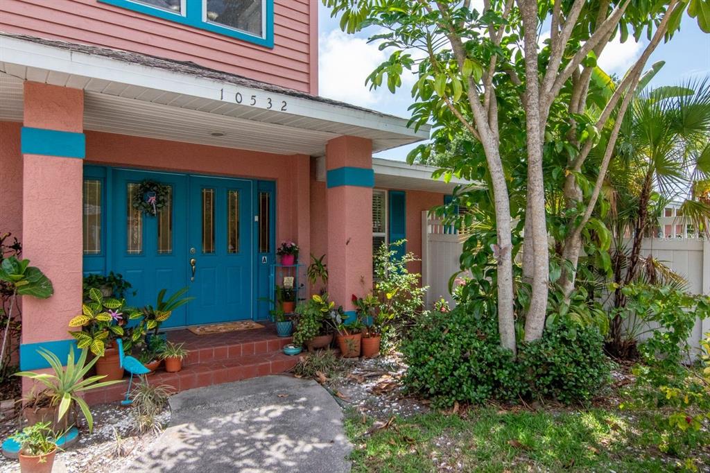 A pink house exterior features a bright blue double front door and a covered porch — 10532 67TH AVENUE, SEMINOLE, FL