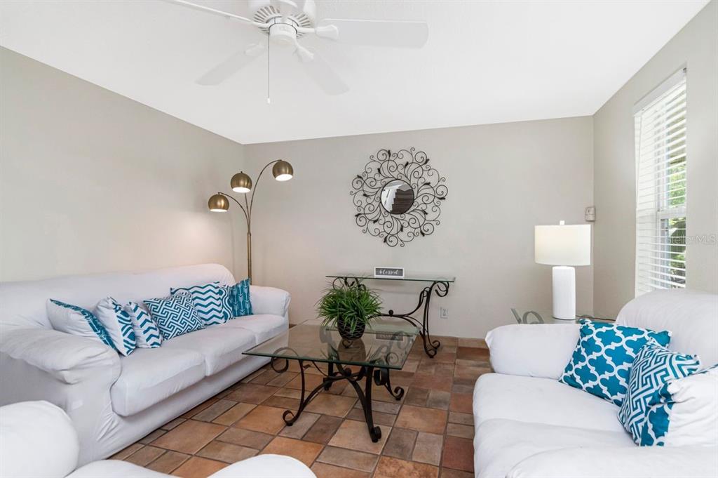 A living room features white sofas, a glass coffee table, and tile flooring — 10532 67TH AVENUE, SEMINOLE, FL