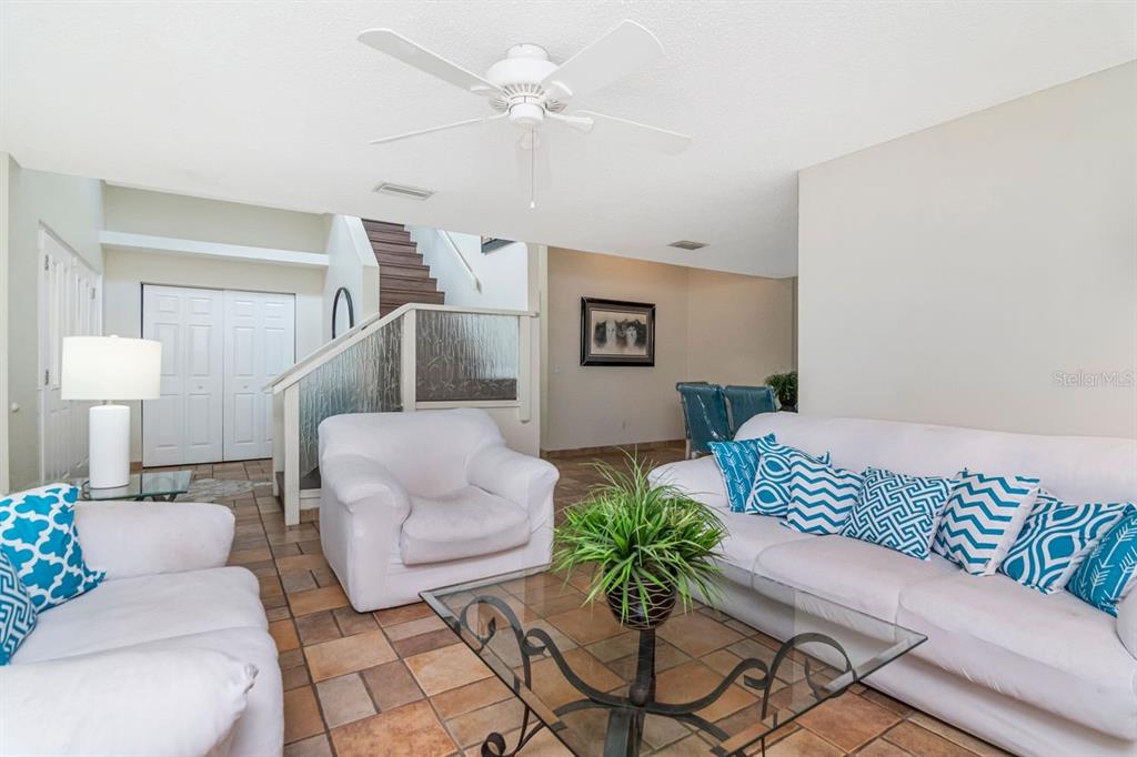 A living room features white sofas, a glass coffee table, and a staircase with glass railings — 10532 67TH AVENUE, SEMINOLE, FL