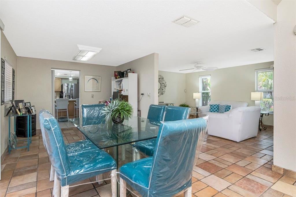 A dining area with a glass table and blue chairs opens into a living room — 10532 67TH AVENUE, SEMINOLE, FL