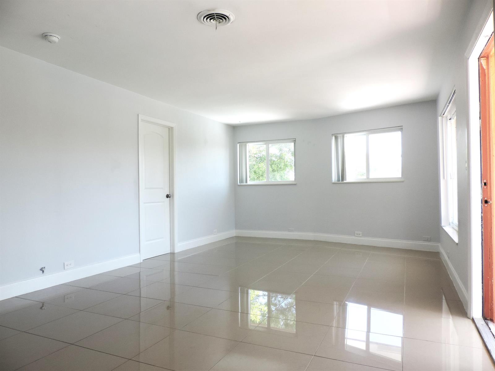 An empty room with light gray walls, large beige floor tiles, and three windows — 915 SE 22nd Avenue, Pompano Beach FL 33062, POMPANO BEACH, FL