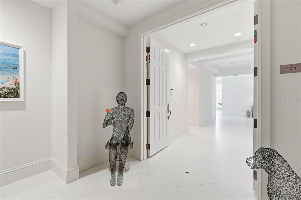 A white-walled entryway features wire sculptures of a person and a dog — 2251 GULF OF MEXICO DRIVE UNIT 301, LONGBOAT KEY, FL