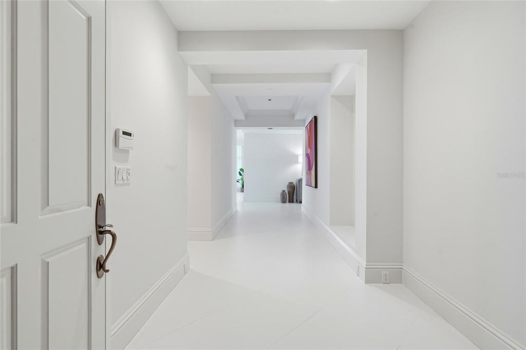 A bright, white hallway features a tray ceiling, tiled floors, and a piece of wall art — 2251 GULF OF MEXICO DRIVE UNIT 301, LONGBOAT KEY, FL