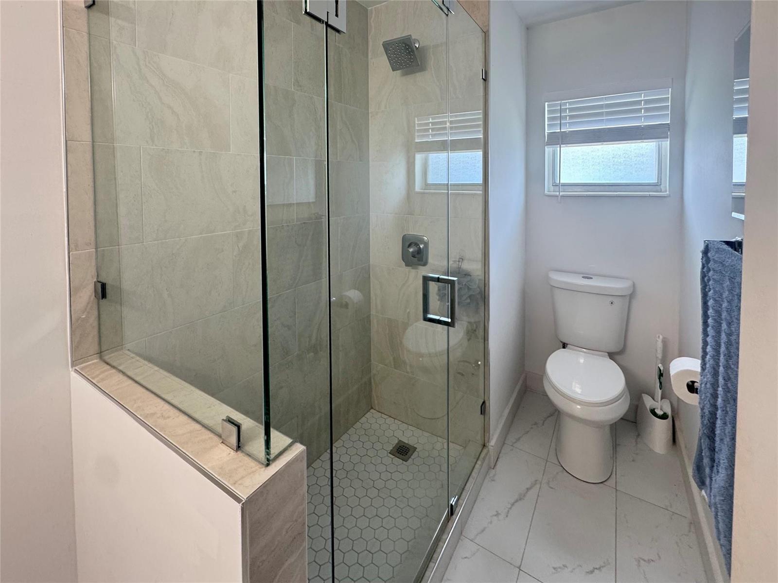 A bathroom features a glass-enclosed walk-in shower with tiled walls and a white toilet — 151 SW 15th Street, Pompano Beach FL 33060, POMPANO BEACH, FL