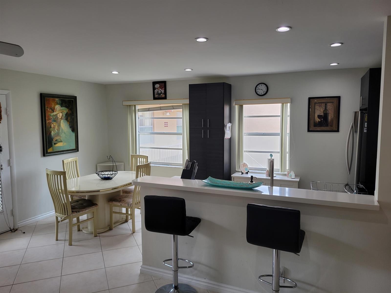 A kitchen and dining area with a breakfast bar, dark cabinets, and tile flooring — 662 Burgundy N, Delray Beach FL 33484, DELRAY BEACH, FL