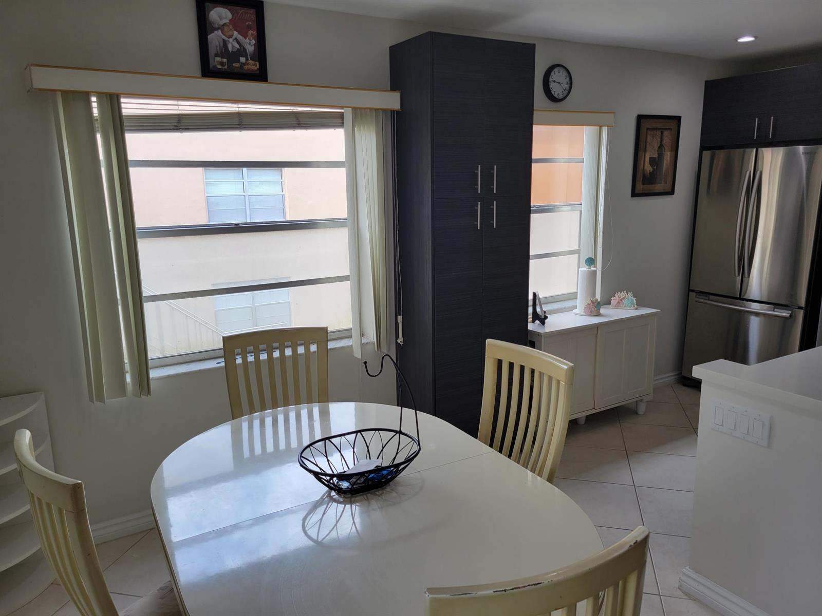 A dining area features a white table, four chairs, a tall dark cabinet, and a refrigerator — 662 Burgundy N, Delray Beach FL 33484, DELRAY BEACH, FL