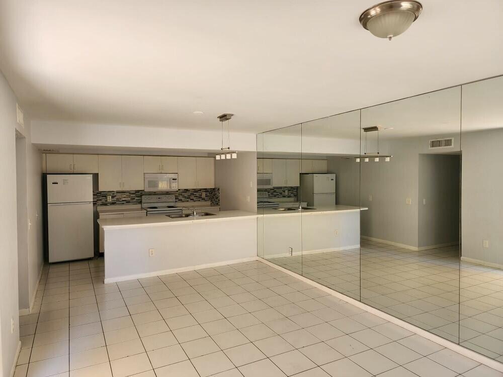 A kitchen with white cabinets and a breakfast bar opens to a tiled dining area — 176 Waterside Drive, Hypoluxo FL 33462, HYPOLUXO, FL