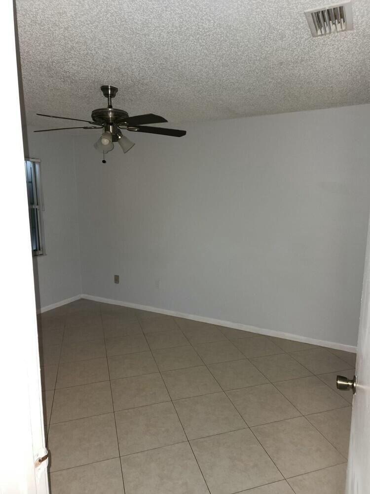An empty room with light gray walls, tile flooring, and a ceiling fan — 176 Waterside Drive, Hypoluxo FL 33462, HYPOLUXO, FL