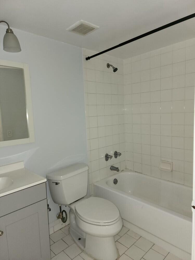 A bathroom features a gray vanity, a white toilet, and a tiled shower-tub combination — 176 Waterside Drive, Hypoluxo FL 33462, HYPOLUXO, FL