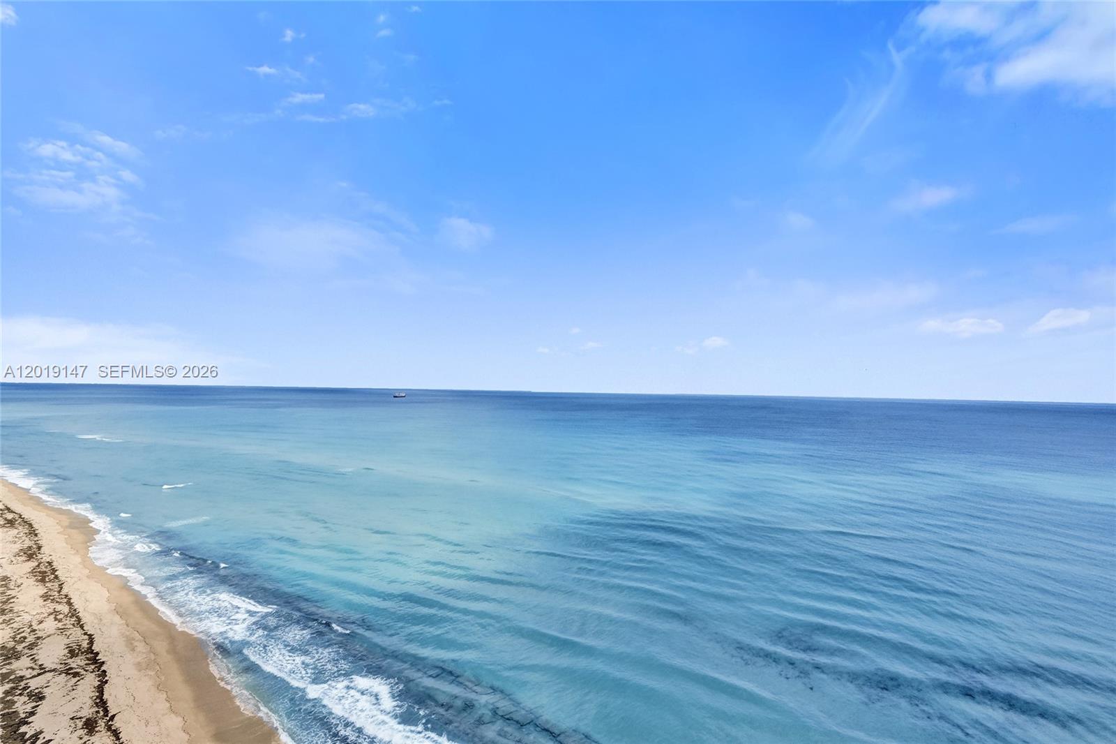 An elevated view of a sandy beach meeting the blue ocean under a clear sky — 5420 N Ocean Dr # 2201, Singer Island FL 33404, SINGER ISLAND, FL
