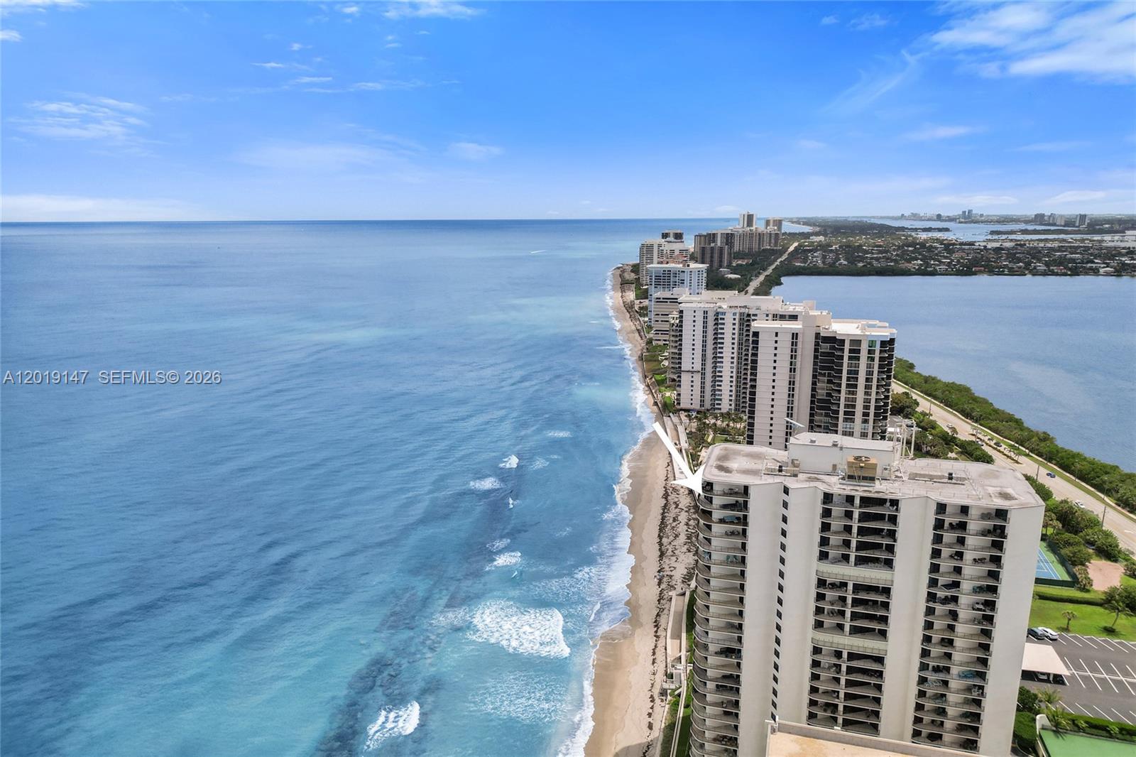 An aerial view shows a high-rise residential building situated along a sandy ocean beach — 5420 N Ocean Dr # 2201, Singer Island FL 33404, SINGER ISLAND, FL