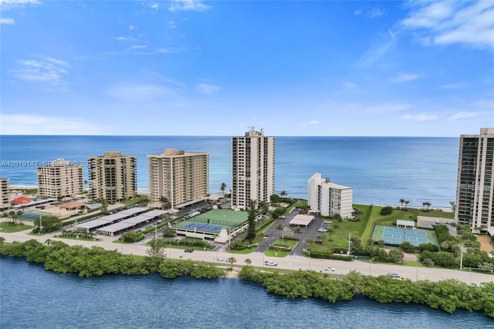 An aerial view shows several high-rise residential buildings situated along a coastline near a road — 5420 N Ocean Dr # 2201, Singer Island FL 33404, SINGER ISLAND, FL
