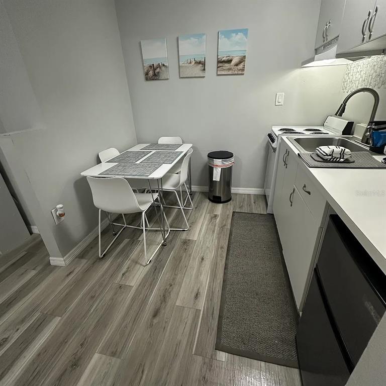 A small kitchen features white cabinets, light wood-look flooring, and a dining table for four — 800 N ATLANTIC AVENUE UNIT 420, DAYTONA BEACH, FL