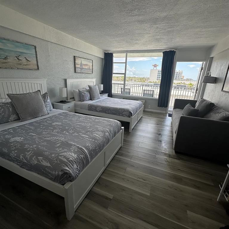 A hotel room features two beds, a gray sofa, and a balcony with ocean views — 800 N ATLANTIC AVENUE UNIT 420, DAYTONA BEACH, FL