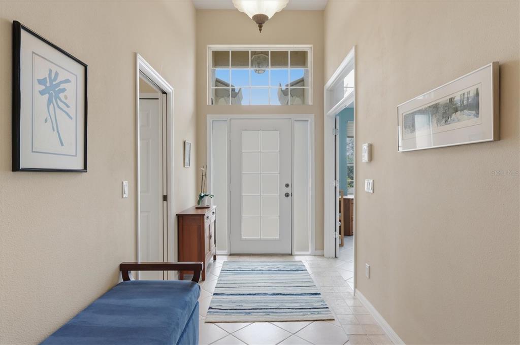 A bright entryway features a white front door, a transom window, and a blue bench — 7235 KENSINGTON COURT, UNIVERSITY PARK, FL