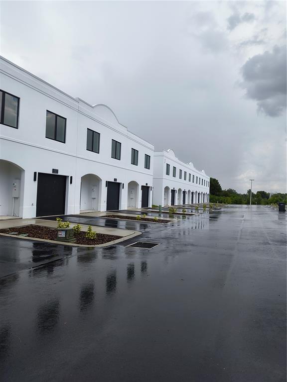 A row of modern white townhouses with black garage doors and arched entryways — 4373 CAMBIO GARDENS COURT, TAMPA, FL