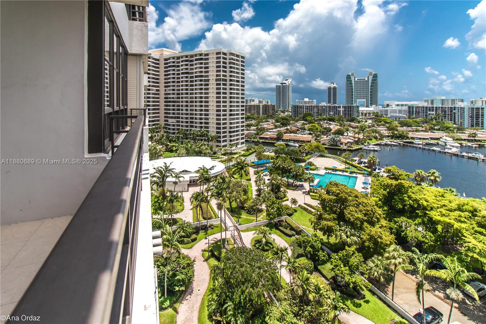 A high-angle view from a balcony overlooks a landscaped courtyard, swimming pool, and marina — 500 Three Islands Blvd # 822, Hallandale Beach FL 33009, HALLANDALE BEACH, FL