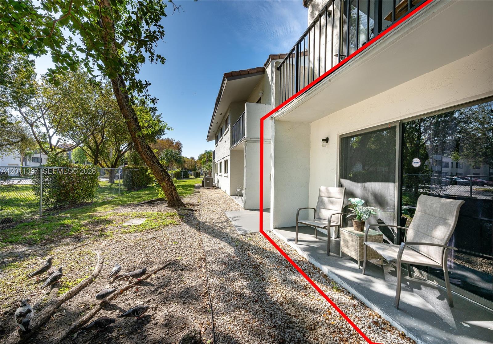 A ground-floor patio with two chairs and a small table sits beside a building — 7095 NW 179th St # 110, Hialeah FL 33015, HIALEAH, FL