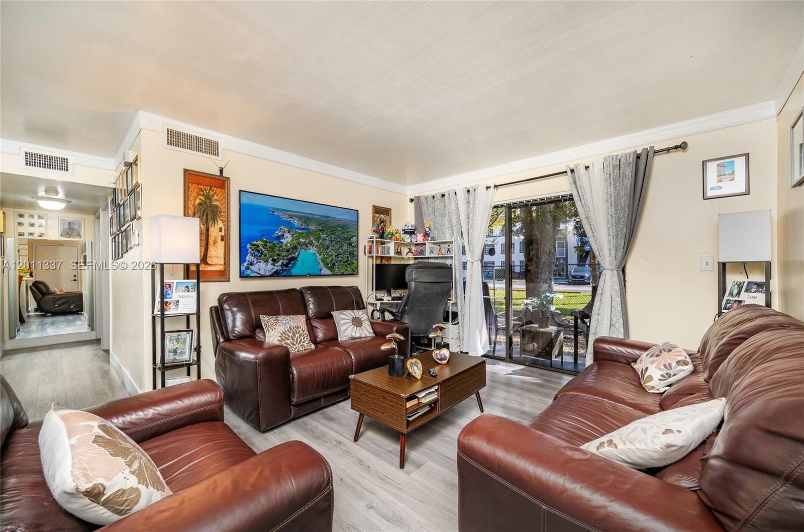 A living room features brown leather sofas, a coffee table, and a sliding glass door — 7095 NW 179th St # 110, Hialeah FL 33015, HIALEAH, FL