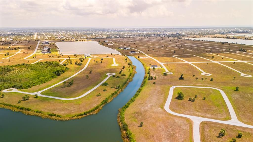 An aerial view shows a winding canal flowing through a large, undeveloped residential subdivision — 14163 PERMIT COURT, PLACIDA, FL