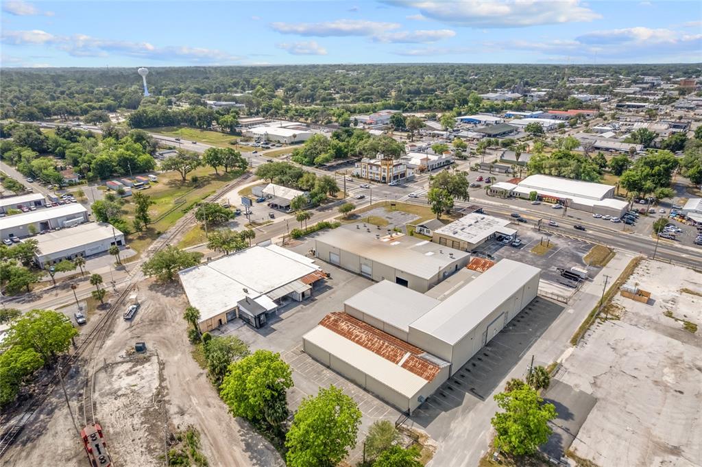 An aerial view shows industrial warehouse buildings with metal roofs situated near a railroad track — 1118 N MAGNOLIA AVENUE, OCALA, FL