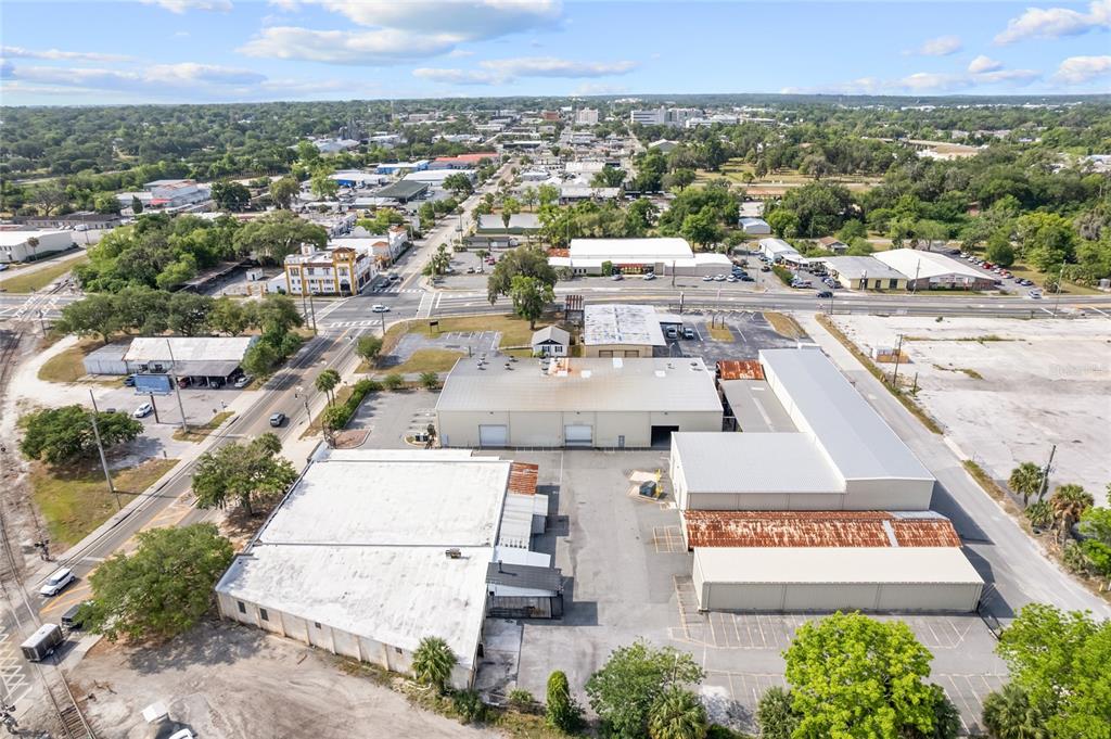 An aerial view shows a commercial warehouse complex with metal roofs and surrounding parking lots — 1118 N MAGNOLIA AVENUE, OCALA, FL