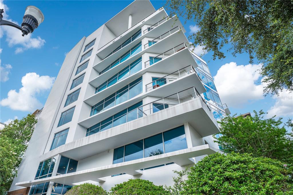 A low-angle view of a modern white mid-rise building with glass balconies and large windows — 525 E JACKSON STREET UNIT 302, ORLANDO, FL